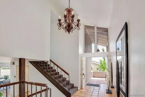 Stunning interior with a grand staircase, ornate chandelier, and elegant artwork.