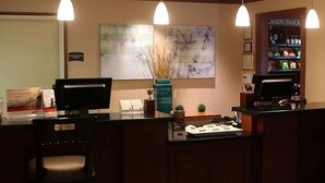 A reception area with a counter, two monitors, a sign for 'CANDY/SNACK', and a painting on the wall. - Better Choice for your Vacation! 2 Posh Units, Free Breakfast, Outdoor Pool! (Vancouver)