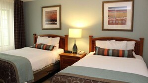 A hotel room with two beds, a nightstand with a lamp, and framed pictures on the wall. - Better Choice for your Vacation! 2 Posh Units, Free Breakfast, Outdoor Pool! (Vancouver)