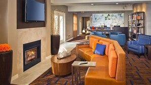 A modern hotel lobby with a fireplace, comfortable seating, a flat-screen TV, and a bar area. - Best Value, Quality Stay! Close to Tinton Falls Recreation Complex, Pet-Friendly (Tinton Falls)