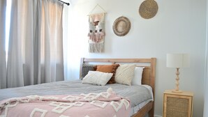 A bedroom with a bed, a bedside lamp, a wall hanging, and a woven wall decoration. - Elegant & Convenient New House at Leppington - 2 min drive from train station! (Leppington)