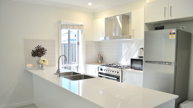 A modern kitchen with white cabinetry, a stainless steel refrigerator, an oven, and a sink. - Elegant & Convenient New House at Leppington - 2 min drive from train station! (Leppington)