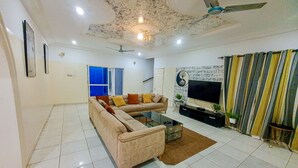 A living room with a sofa, coffee table, TV, ceiling fan, and a patterned wall.