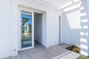 A modern exterior with a sliding glass door leading to a covered patio area.