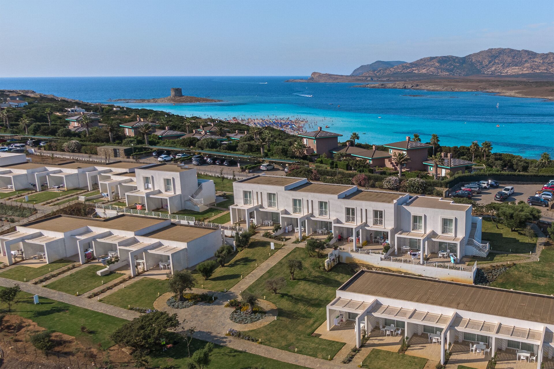 Une station balnéaire dotée de villas modernes, d’une plage et, au loin, d’une structure qui ressemble à un château.