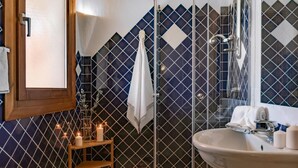 Un baño con pared de azulejos, un lavamanos, un espejo y una zona de ducha.