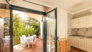 A modern kitchen with white cabinets, a sink, and a dining area with a table and chairs. - Quaint Residence I Mirti Bianchi 1 Bedroom Sleeps 2 persons - Bilo 2 (Santa Teresa Gallura)