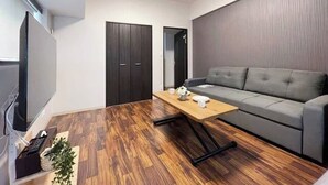 Una sala de estar moderna con un sofá gris, una mesa de centro de madera y un televisor montado en la pared.