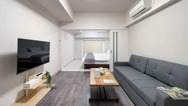 Une chambre d’hôtel moderne équipée d’un téléviseur à écran plat, d’un canapé, d’une table basse en bois et d’un lit en arrière-plan.