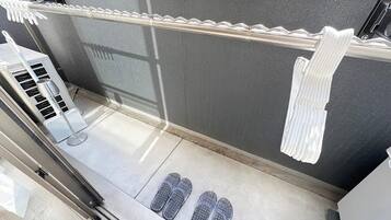 Un baño moderno con zona de ducha, un perchero y un par de pantuflas en el suelo.