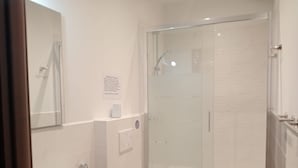 Une salle de bain moderne avec une douche à parois de verre, un lavabo blanc et des toilettes.
