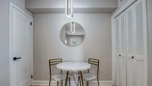 A room with a round table and two chairs, a mirror on the wall, and a set of white louvered closets. - Chic Riverfront apartment in downtown San Marco (Jacksonville)