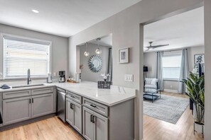 A modern kitchen with grey cabinetry, a central island, and pendant lighting.