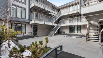 Un bâtiment moderne doté de nombreux balcons, d’escaliers et d’une cour intérieure agrémentée de plantes en pot.