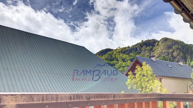 Una cabaña de montaña con techo de metal corrugado y terraza de madera.