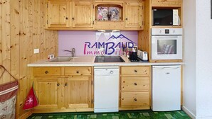 A compact kitchen with wooden cabinets, a microwave, a toaster, and a dishwasher.