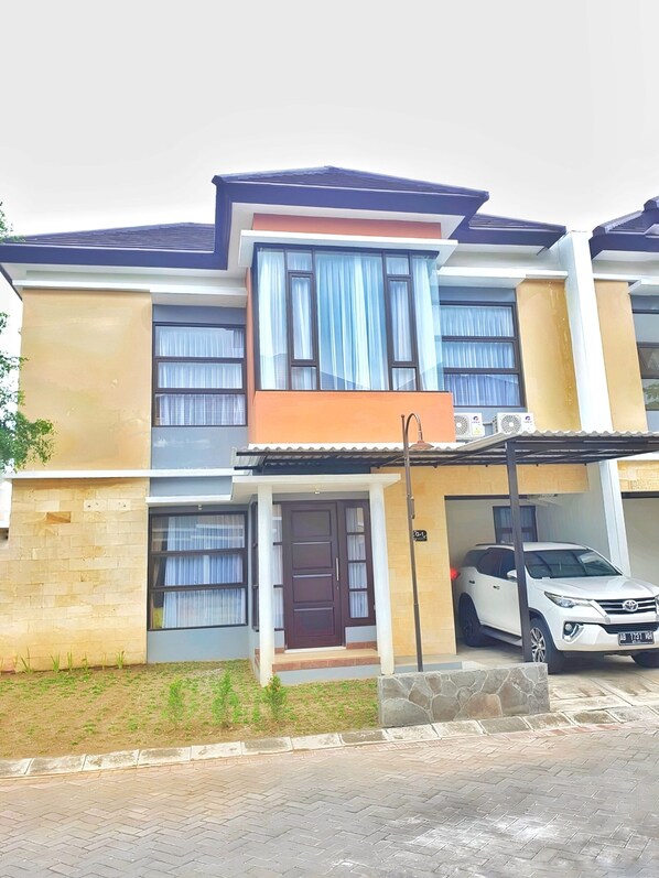 Stylish two-story residence with a flat roof and covered entrance, featuring a garage and paved outdoor space.