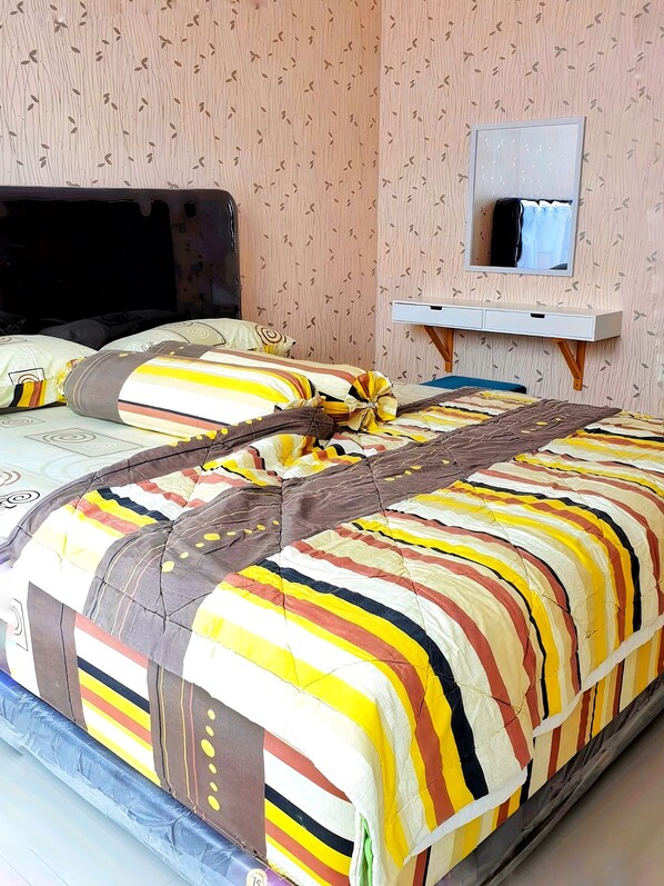 A bedroom with a bed, a bedside table, a mirror, and a wardrobe.