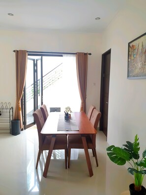 Enjoy meals in this dining area with a large table and six chairs, surrounded by a balcony with a door.