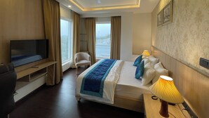 Una habitación de hotel con una cama, televisión, una silla y una lámpara.