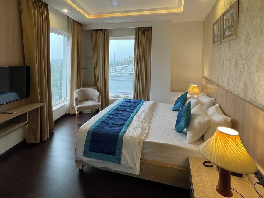Una habitación de hotel con una cama, televisión, una silla y una lámpara.