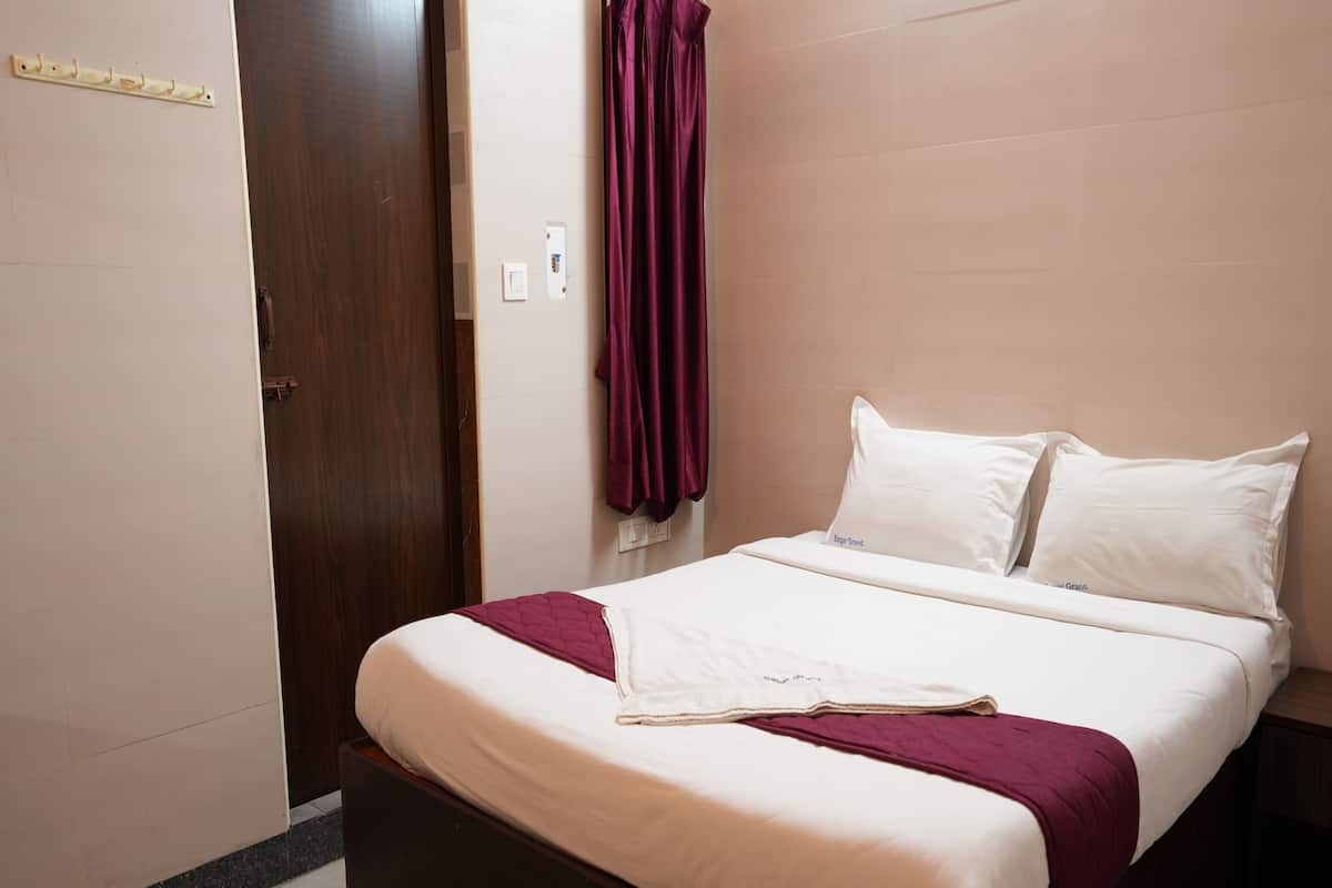 Cama bem arrumada com roupa de cama branca e vinho, cabeceira de madeira e chão de mármore.