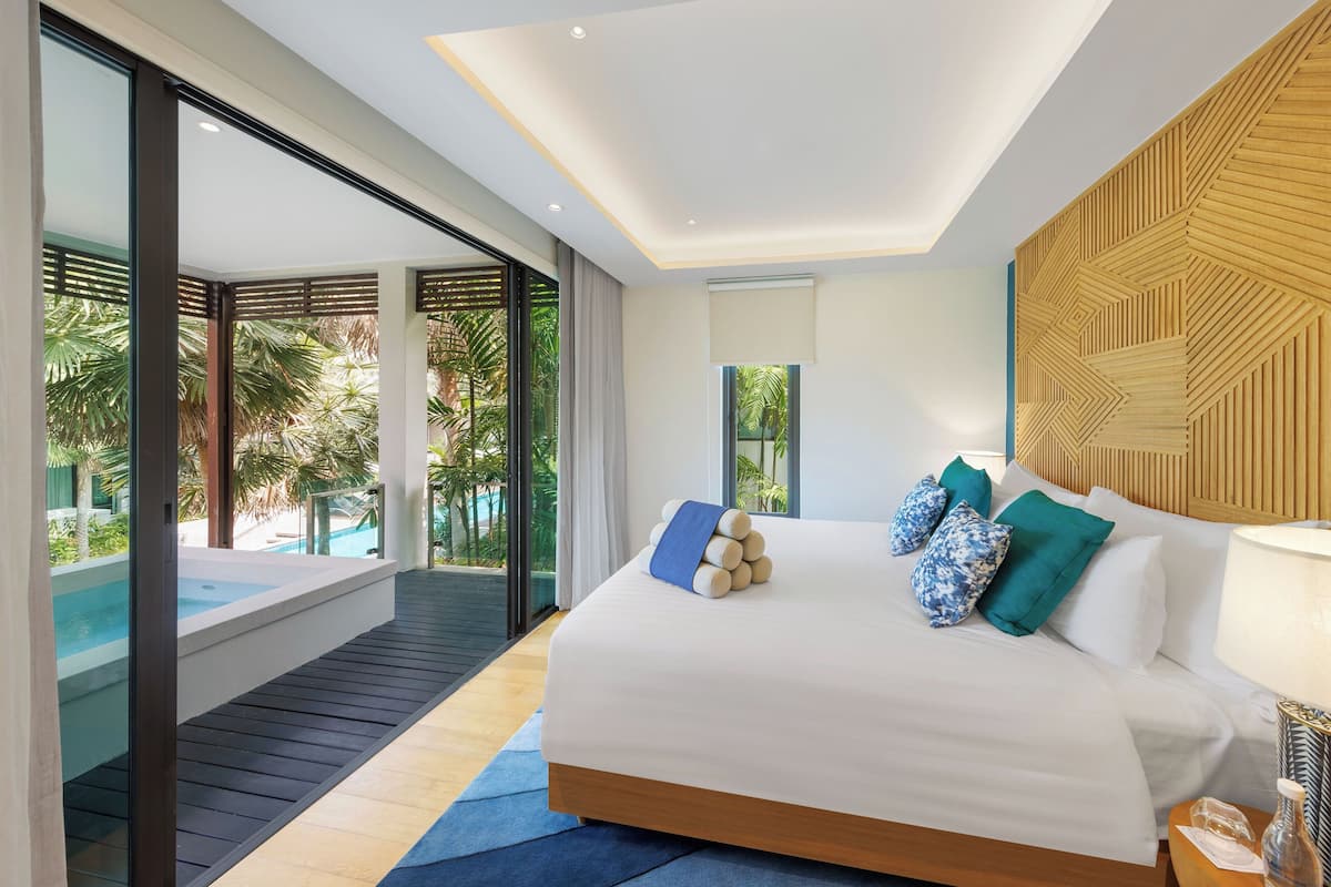 Ein modernes Hotelzimmer mit einem großen Bett, Blick auf den Pool und einem Balkon.