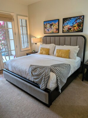 A neatly made bed with a striped blanket, a nightstand with a lamp, and two framed pictures on the wall.