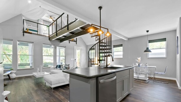 A spacious kitchen with a central island, a staircase, and a dining area with a table and chairs. - Secret Pool Cabana- Mins to Downtown and Beach (St. Augustine)