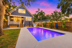 Un jardin à l’arrière d’une maison d’habitation, avec une piscine, une véranda et une clôture en bois.