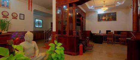 Un interior tradicional con mobiliario de madera, una estatua de Buda y un candelabro.