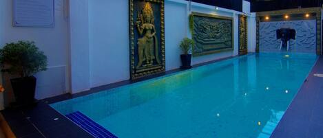 Una piscina con detalles decorativos en la pared y una planta en maceta.