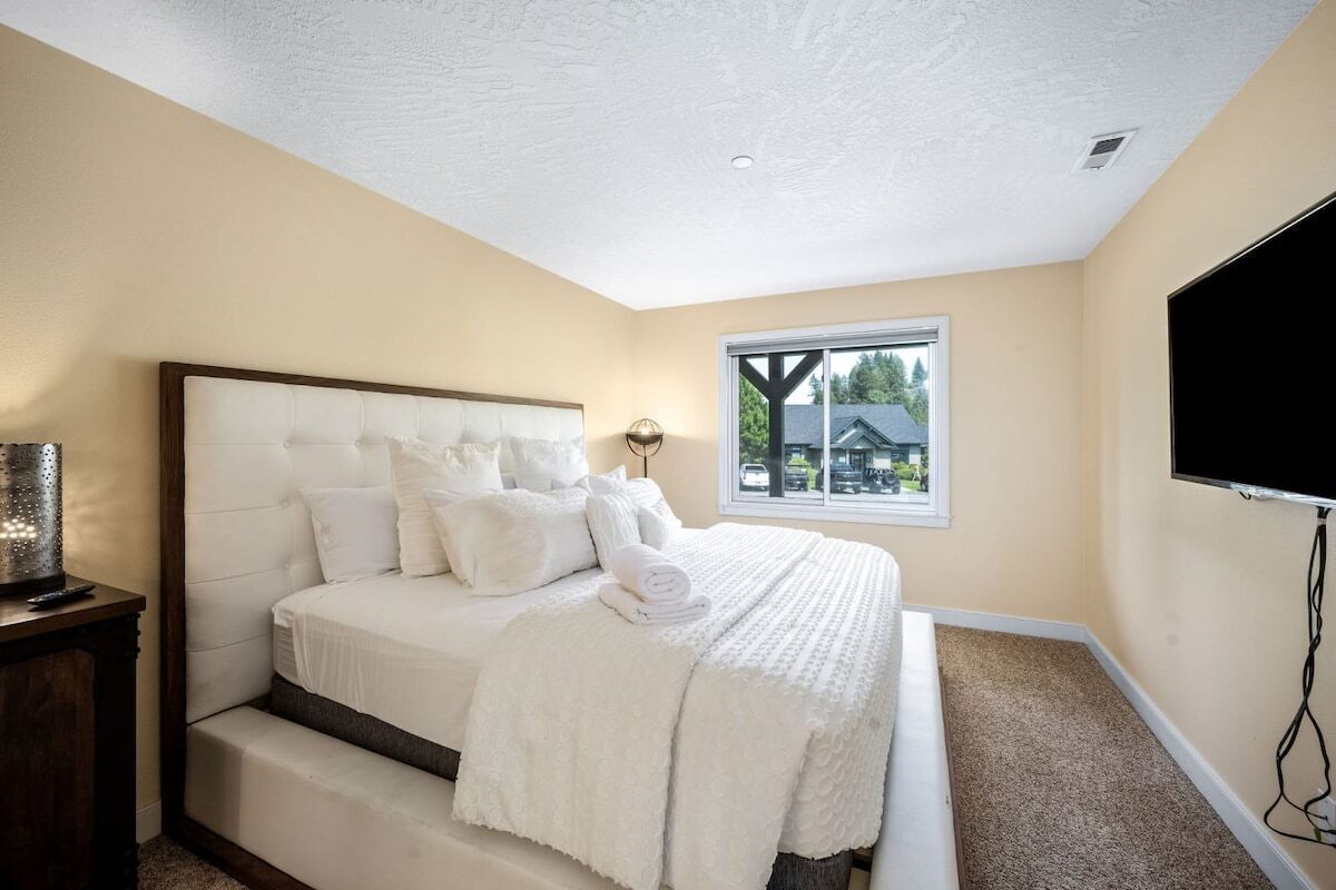 Un dormitorio con una cama grande, un ventanal con vistas y un televisor de pantalla plana montado en la pared.