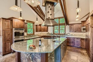 A spacious kitchen with wooden cabinets, a large island, and a stone floor. - Prime location | Pet friendly | 30 Day Rental (Breckenridge)
