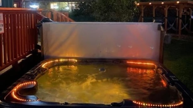 A hot tub with LED lights, surrounded by a wooden deck and a house. - Bugsy's By the Beach ~ Hot Tub, Hammock Station & A/C (Long Beach)