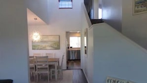 A hallway leading to a dining area with a table and chairs, a staircase, and a sign reading "Beach House". - Bugsy's By the Beach ~ Hot Tub, Hammock Station & A/C (Long Beach)