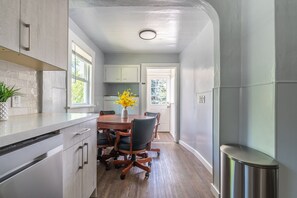A modern kitchen with a wooden dining table, chairs, and a vase of yellow flowers.