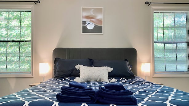 A neatly made bed with a patterned bedspread, two pillows, and a folded blanket on a headboard. - Cozy 2-bedroom Townhouse in Kennesaw, Centrally Located. (Kennesaw)