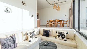 A modern living room with a sofa, coffee table, and dining area.
