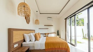 A modern bedroom with a large bed, wooden headboard, and a view of a garden through large windows.