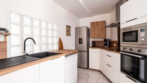Une cuisine moderne équipée d’un lave-vaisselle, d’un réfrigérateur, d’un four à micro-ondes et d’un four traditionnel.