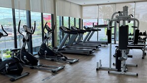 Un gimnasio con cintas de correr, elípticas y equipo de pesas.