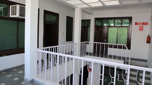 A corridor with white railings, a ceiling with a grid pattern, and doors with green-tinted windows. - Hotel Axiom Prime (Lucknow)