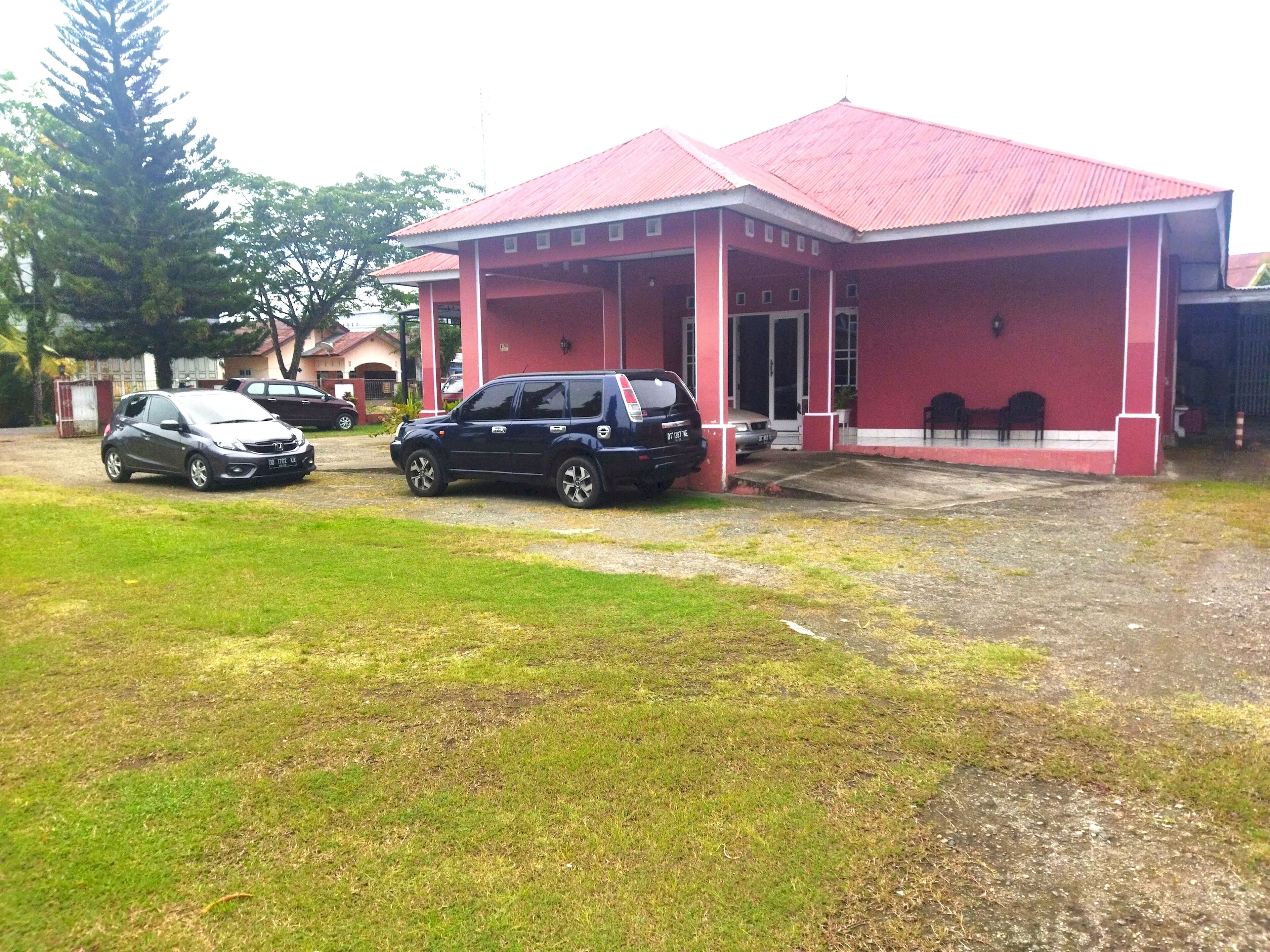 Un edificio con techo rojo y zona de estacionamiento techada.