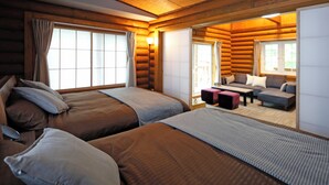 A log cabin-style room with two beds, a sofa, and a small table. - THE LODGE ABASHIRI (Abashiri)