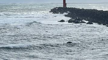 Um farol em um afloramento rochoso, com ondas batendo nele.