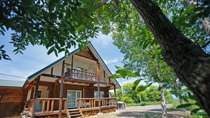 A log cabin with a balcony, a porch, and a gravel driveway. - THE LODGE ABASHIRI (Abashiri)