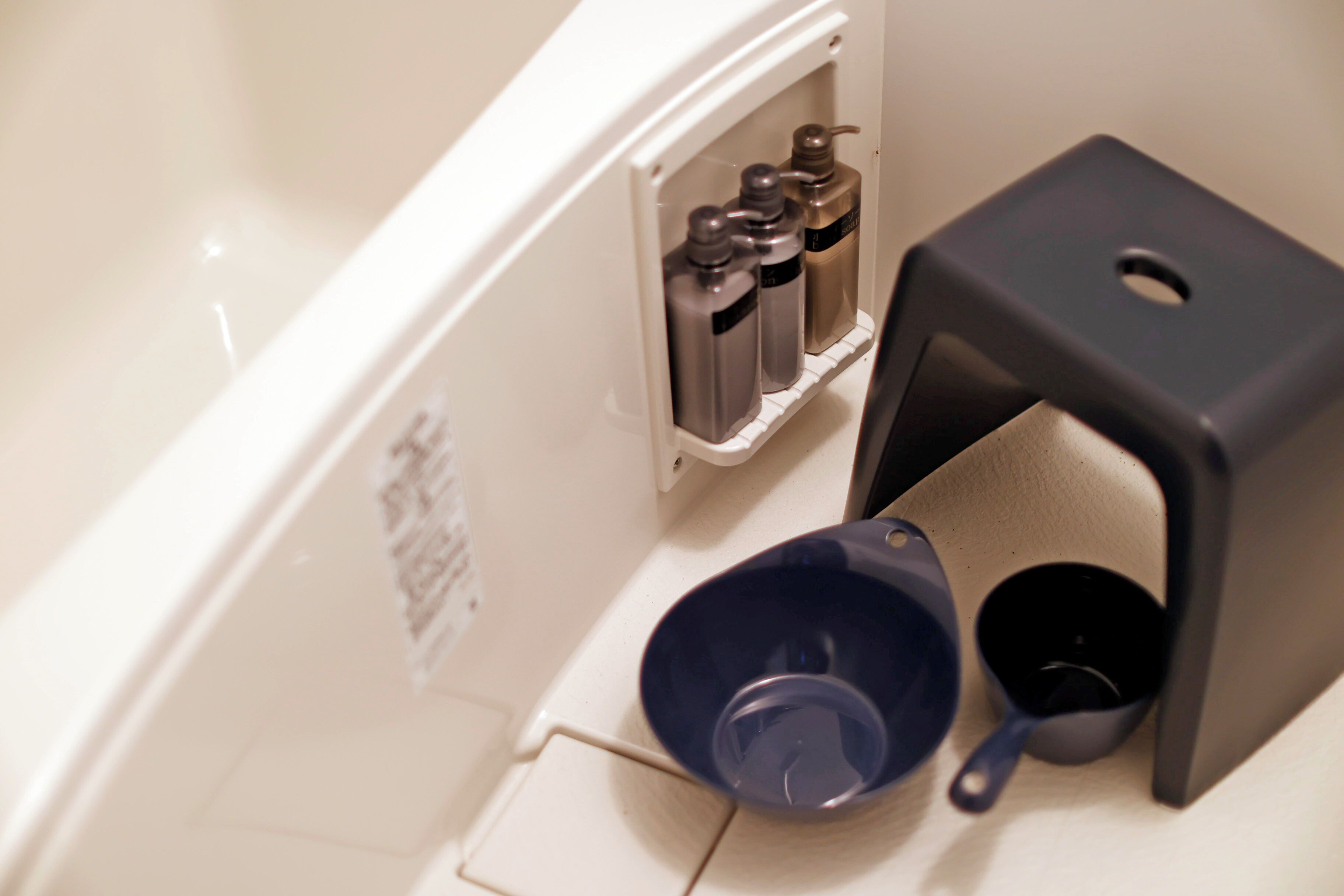 Un baño con una bañera blanca, un lavabo azul y un dispensador de jabón negro.