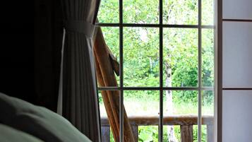 Una stanza con un'ampia finestra e un balcone in legno, con un letto e biancheria verde.