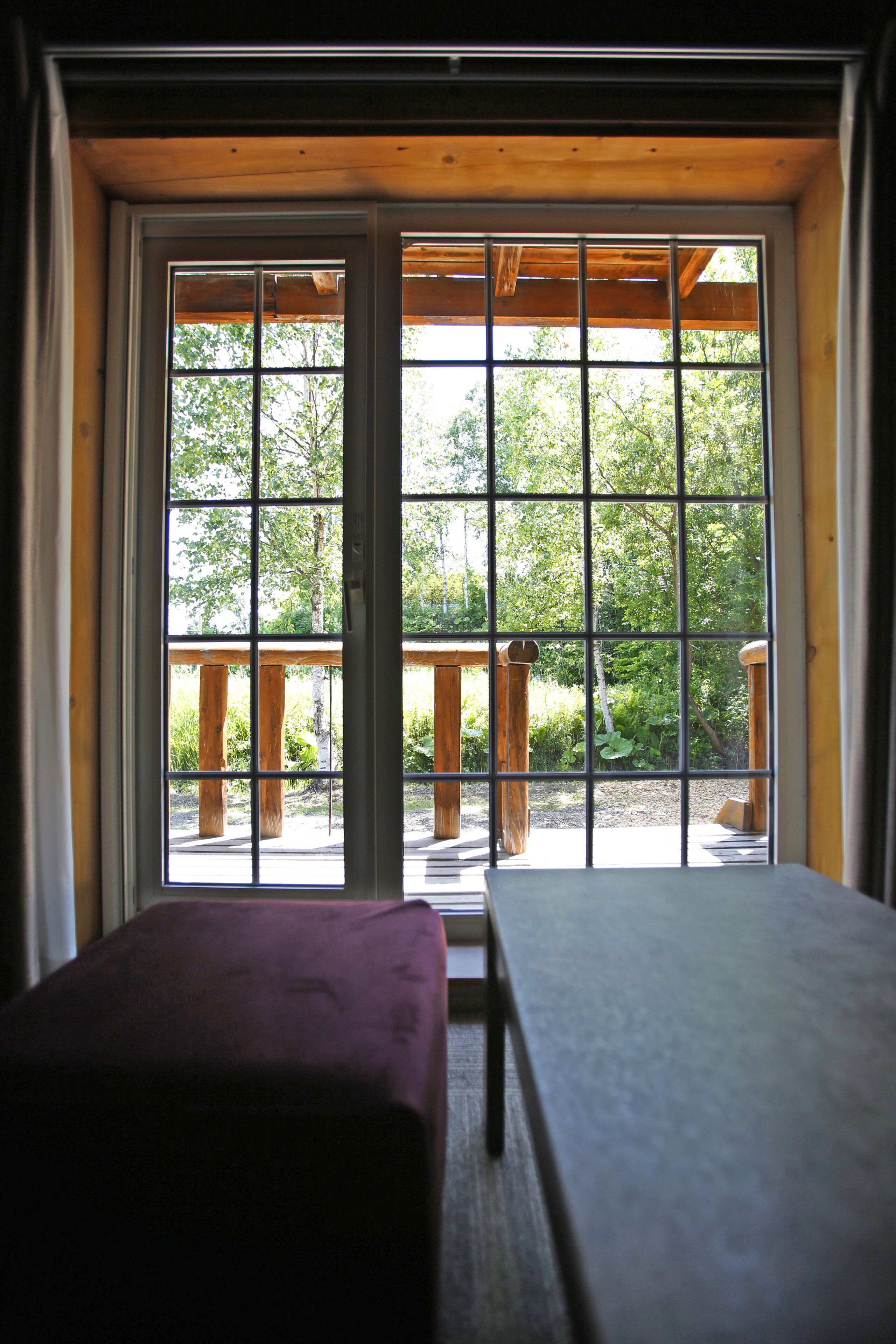 A room with a large window, a wooden bench, and a table.